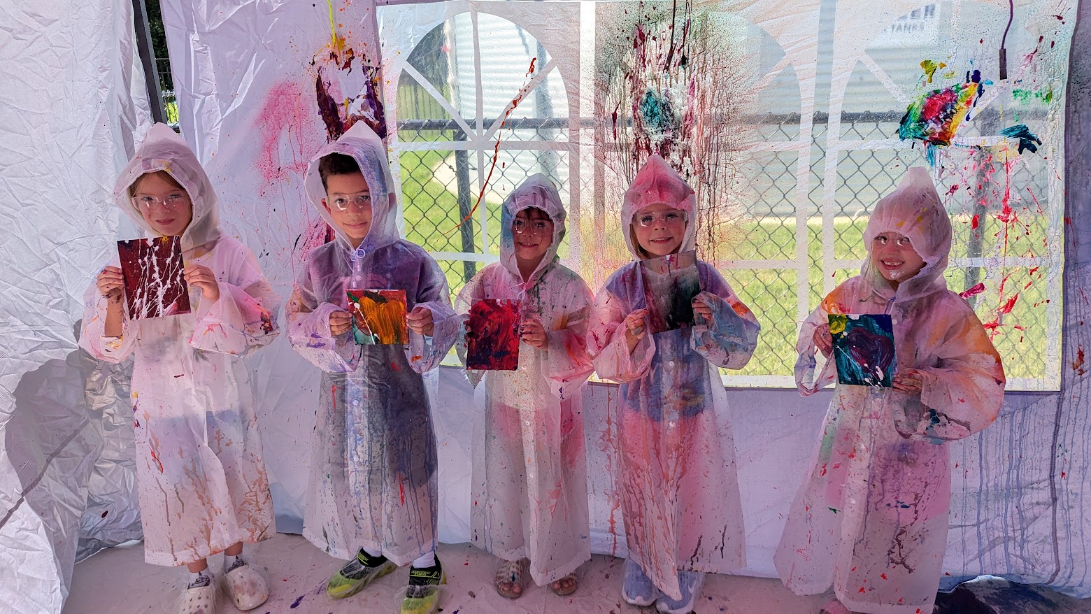 Young creators showing their finished splatter-paint artwork